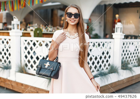 Cheerful young girl in a pink dress with handbag Cheerful young girl in a pink dress with handbag 49437626