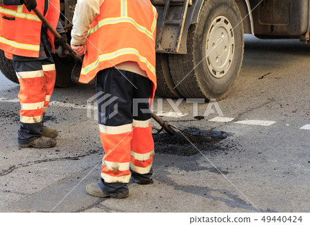 Two road builders assemble and level fresh asphalt 49440424