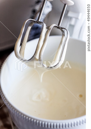 Electric mixer being used to mix ingredients for a 49444650