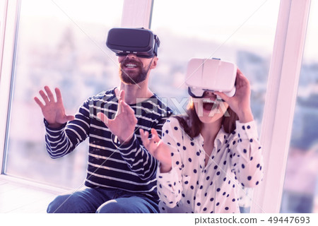 Positive delighted couple sitting in VR mask on faces 49447693