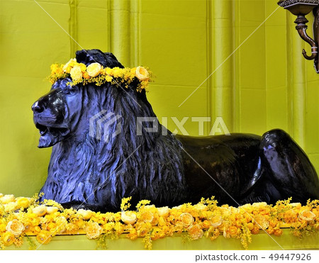 Lion statue decorated with yellow flowers Lion statue decorated with yellow flowers 49447926