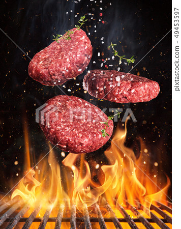 Tasty beef steaks flying above cast iron grate with fire flames. Tasty beef steaks flying above cast iron grate with fire flames. 49453597