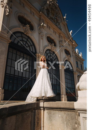 Beautiful bride in luxury wedding dress in front of palace 49454498