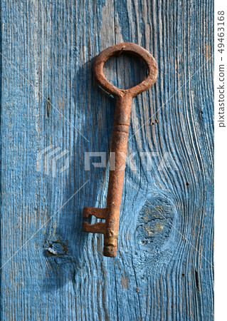 Old handmade metal key hanging on wooden wall 49463168