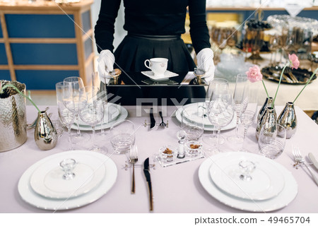 Waitress with tray puts the dishes, table setting Waitress with tray puts the dishes, table setting 49465704