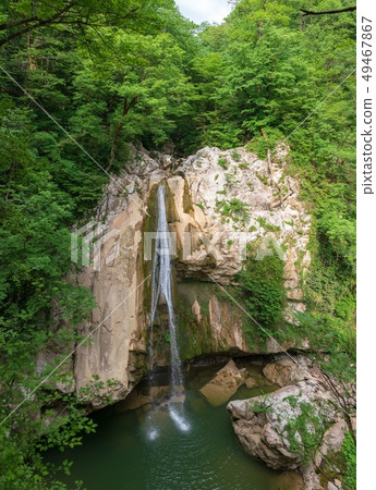 A high waterfall falls from a cliff 49467867