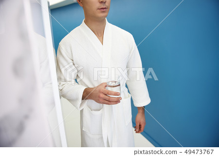Young man walk in spa center with glass water Young man walk in spa center with glass water 49473767