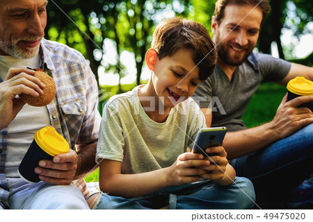 Family Picnic. Boy Watch Smartphone. Men Smile. Family Picnic. Boy Watch Smartphone. Men Smile. 49475020