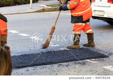 A road builder collects fresh asphalt 49476836