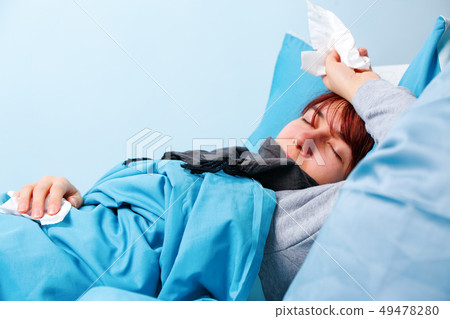 Photo of sick woman with paper handkerchiefs lying on bed Photo of sick woman with paper handkerchiefs lying on bed 49478280