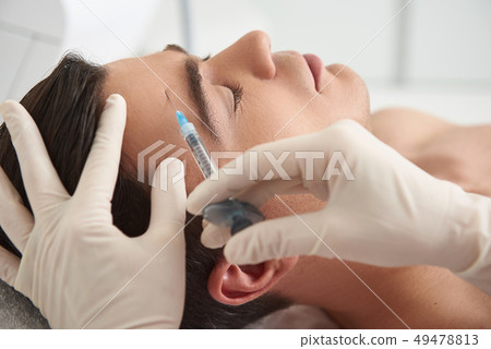 Man on beauty injection procedure of forehead skin Man on beauty injection procedure of forehead skin 49478813