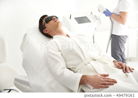 Young man lying on couch in laser epilation center Young man lying on couch in laser epilation center 49479161
