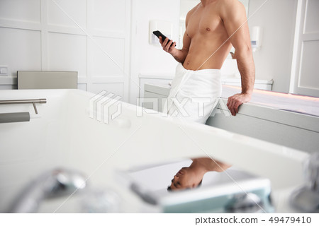 Young muscular man with phone in spa center Young muscular man with phone in spa center 49479410