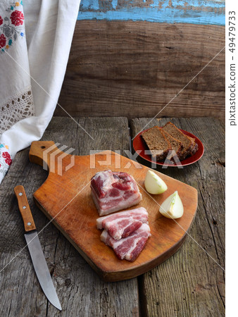 Bacon and bread on an old board. Bacon and bread on an old board. 49479733