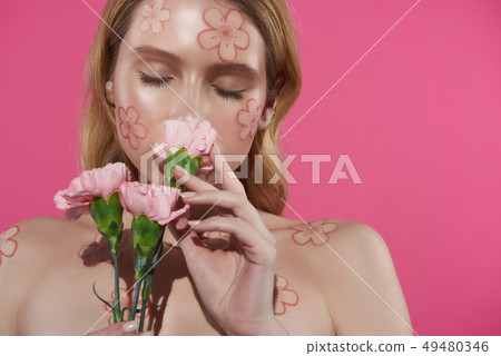 Tender blonde woman smelling carnation in hand Tender blonde woman smelling carnation in hand 49480346