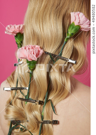 Close up rosy carnation in blonde hair of lady 49480582