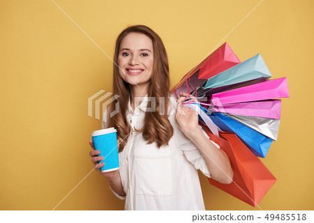 Waist up of beautiful happy young woman enjoying shopping and drinking beverage 49485518