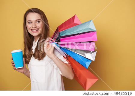 Waist up of beautiful happy young woman enjoying shopping and drinking beverage 49485519