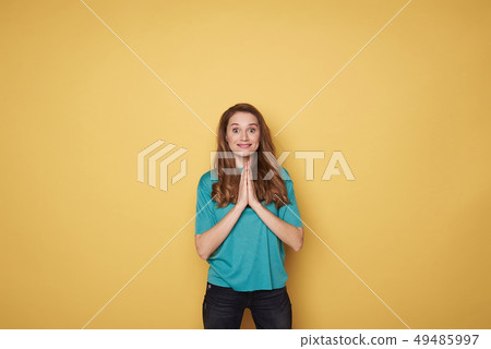 Portrait of brown-haired surprised smiling girl meditating on yellow background 49485997
