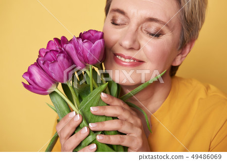 Portrait of charming happy woman with purple tulips in arms Portrait of charming happy woman with purple tulips in arms 49486069