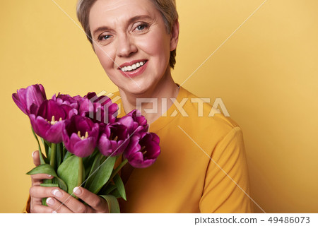 Portrait of charming smiling woman with cute bouquet of tulips in arms Portrait of charming smiling woman with cute bouquet of tulips in arms 49486073