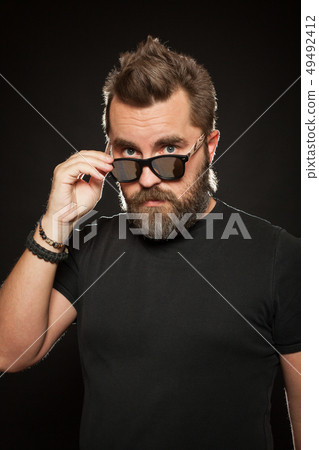 A handsome man wears sunglasses and smiles. 49492412