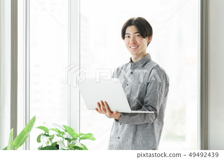 Freelance engineer operating a PC at the window 49492439