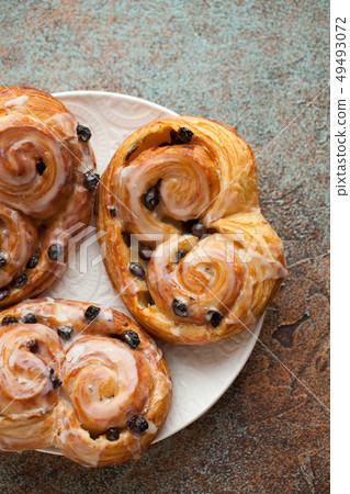 Fresh buns with raisins and icing. 49493072