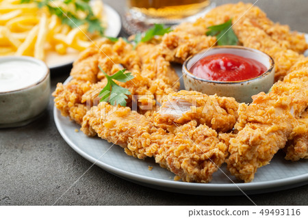 Breaded chicken strips with sauce. 49493116