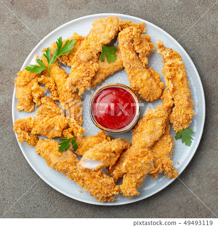 Breaded chicken strips with sauce. 49493119