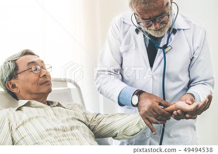 Mature doctor and senior patient in hospital ward. Mature doctor and senior patient in hospital ward. 49494538