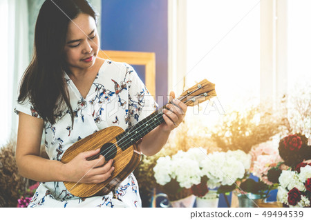 Happy woman musician playing ukulele in studio. 49494539