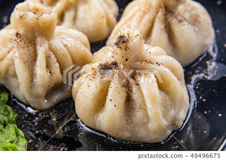 Georgian dumplings Khinkali with meat and red papper, on brown plate Georgian dumplings Khinkali with meat and red papper, on brown plate 49496675