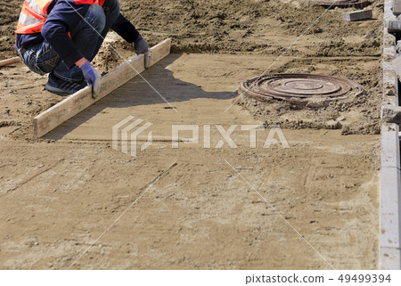Worker aligns the sandy foundation with board 49499394