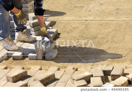 The worker lays the pavement slabs on the prepared 49499395