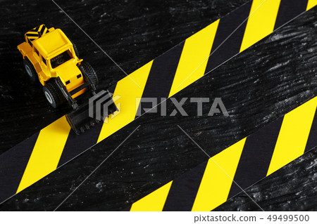 Toy excavator yellow on a black textural Toy excavator yellow on a black textural 49499500