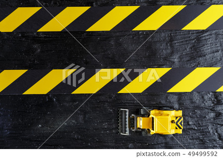 Toy excavator yellow on a black textural Toy excavator yellow on a black textural 49499592