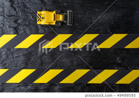 Toy excavator yellow on a black textural Toy excavator yellow on a black textural 49499593