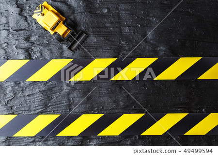 Toy excavator yellow on a black textural Toy excavator yellow on a black textural 49499594
