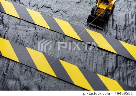 Toy excavator yellow on a black textural 49499595