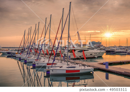 Pink sunset in the sea harbor with moored yachts. Pink sunset in the sea harbor with moored yachts. 49503311