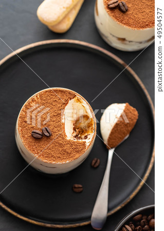 Delicious Italian dessert tiramisu, chocolate, cocoa and coffee beans on a black background. Top 49504577