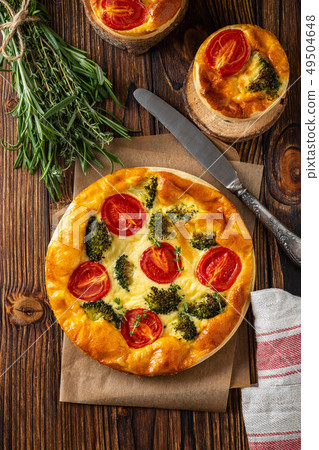 Vegetable pie with broccoli, peas, thyme. tomatoes and cheese on wooden background. Copy space. Vegetable pie with broccoli, peas, thyme. tomatoes and cheese on wooden background. Copy space. 49504648