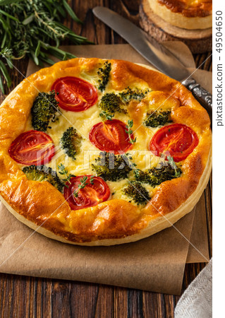 Vegetable pie with broccoli, peas, thyme. tomatoes and cheese on wooden background. Copy space. Vegetable pie with broccoli, peas, thyme. tomatoes and cheese on wooden background. Copy space. 49504650