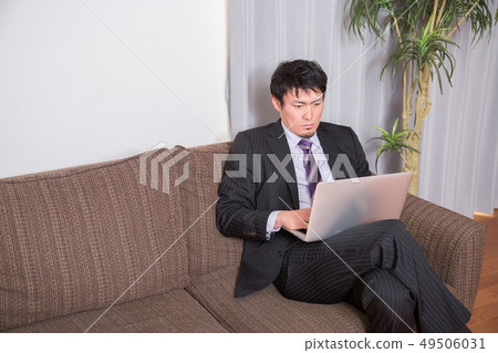 A man who opens a PC on a sofa (thinks) 49506031