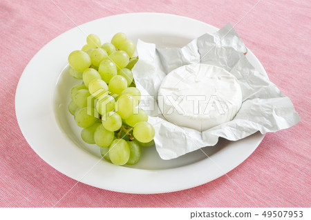 Open package of camembert and grapes on white plat Open package of camembert and grapes on white plat 49507953