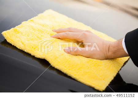 Cleaning car. Man holds the microfiber in hand and polishes the car Cleaning car. Man holds the microfiber in hand and polishes the car 49511152