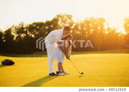 Dad Teaches Kid to Take Shot Golfing Family Hobby. 49512939