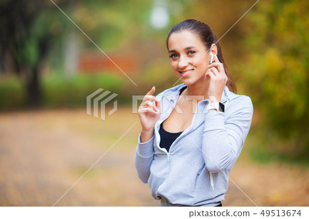 Photo of Joyful Fitness Woman 30s in Sportswear Touching Bluetooth Earpod and Holding Mobile Phone Photo of Joyful Fitness Woman 30s in Sportswear Touching Bluetooth Earpod and Holding Mobile Phone 49513674