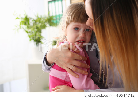 Doctor hugging scared crying little baby girl visiting her office 49514712